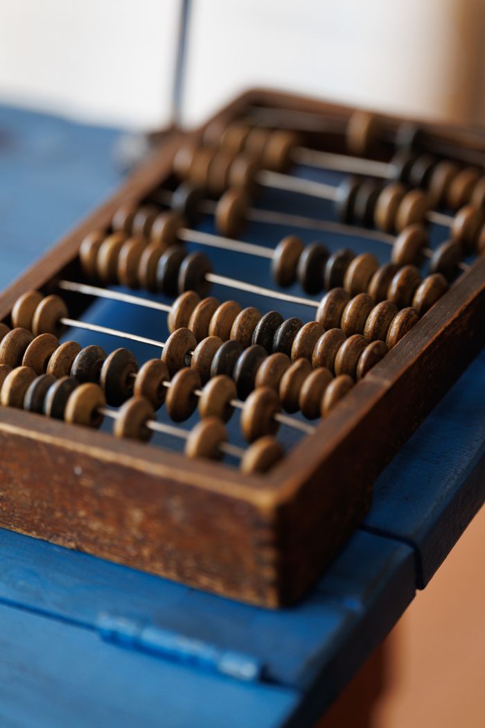A close-up of a classic wooden abacus displaying rows of counting beads on a blue surface.